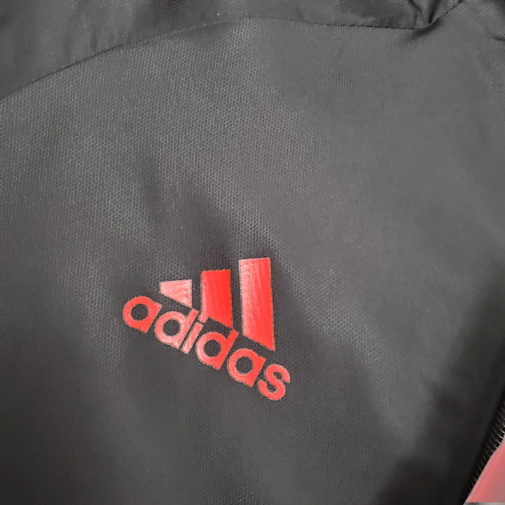 Chaqueta Cortavientos Real Madrid Negra 2021 (Borde Blanco y Rojo)